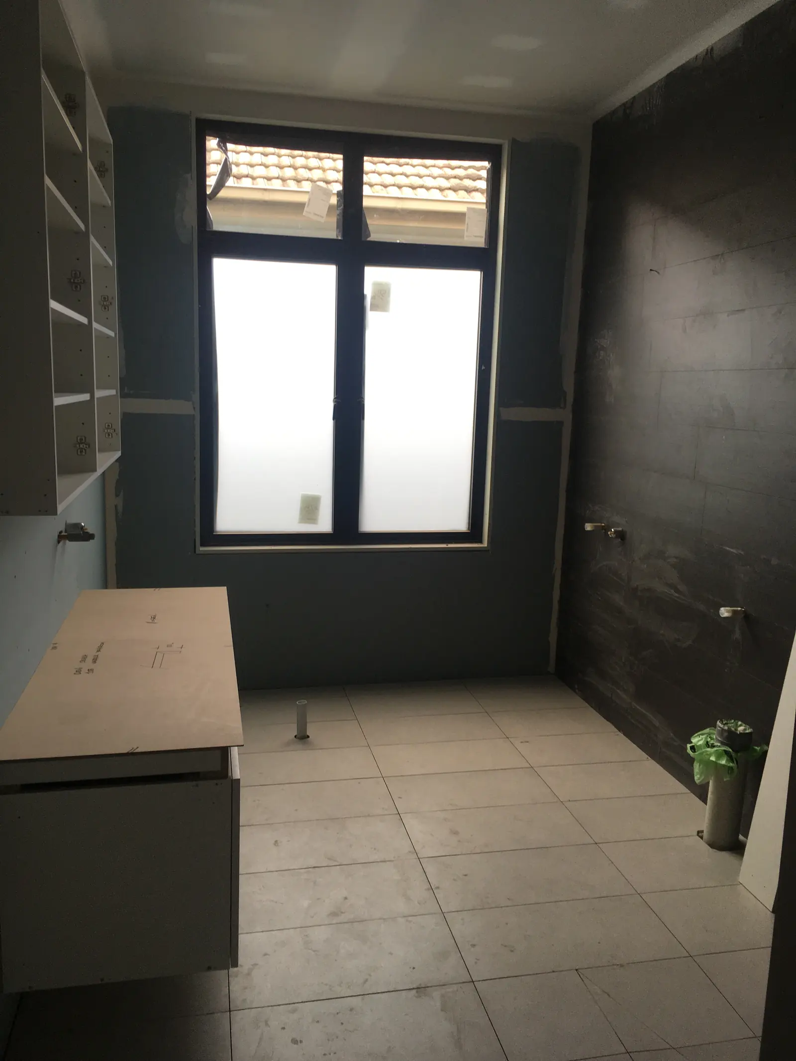 Bathroom at rough-in, with wet-area wall linings, floor tiles and vanity carcass