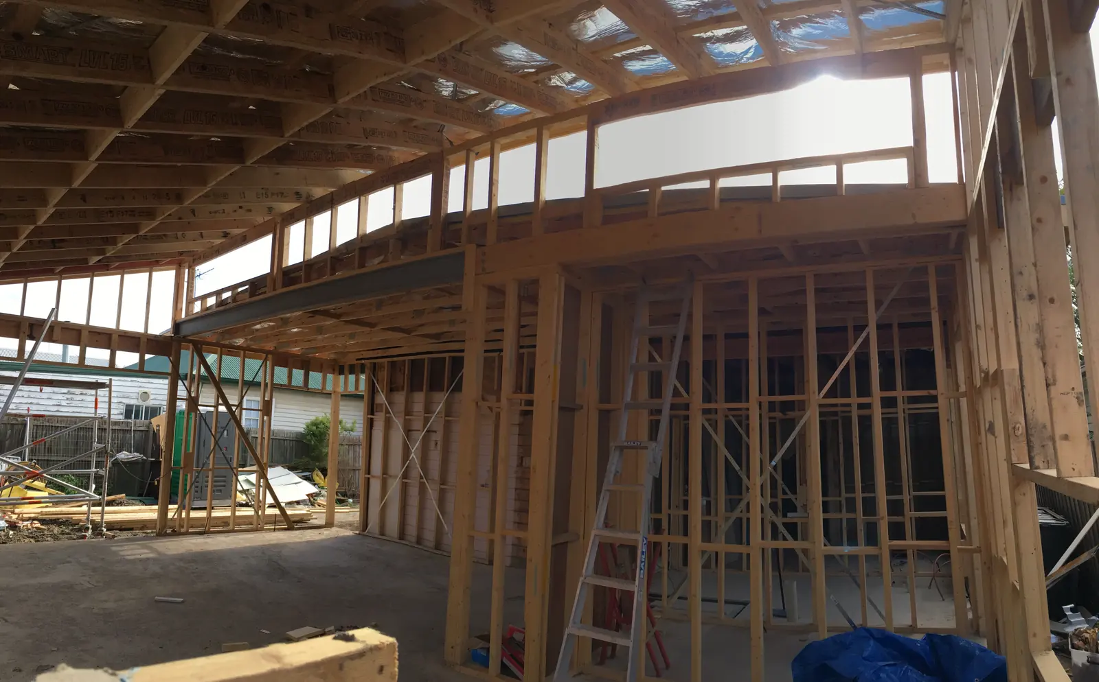 Framing stage inside the extension, showing a steel beam and LVL roof members over the new living area